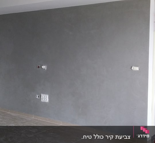 קיר צבוע באפור עם דלי צבע על הרצפה